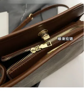 Detail of light gold metal zipper and twist lock on a brown leather tote bag