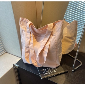 Detail of light pink waterproof nylon tote bag showing soft texture in natural light
