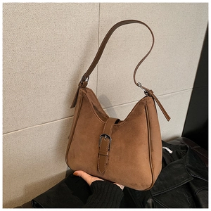 Dettaglio della texture in pelle scamosciata marrone e fibbia in metallo sulla borsa