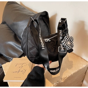 Gros plan du sac hobo en nylon noir matelassé avec large bandoulière lettrée