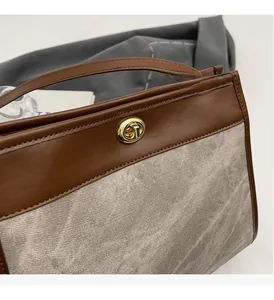 Detail of grey striped fabric tote bag with premium gold turn-lock and leather handle
