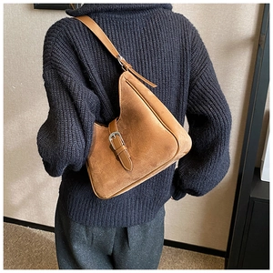 Borsa hobo in camoscio caramello con fibbia d'argento indossata su un maglione scuro
