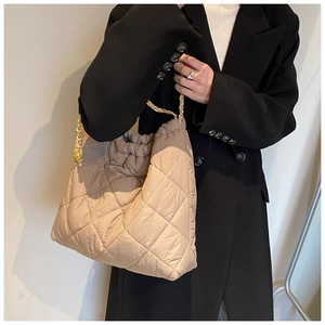 Gros plan du sac seau matelassé beige en tissu Oxford avec bandoulière chaîne dorée