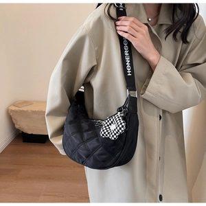 Détail du sac croissant en nylon noir matelassé avec large bandoulière et pendentif