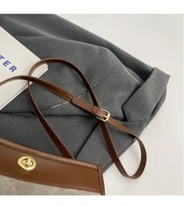 Detail of adjustable brown leather strap and gold metal twist lock on a vintage tote bag