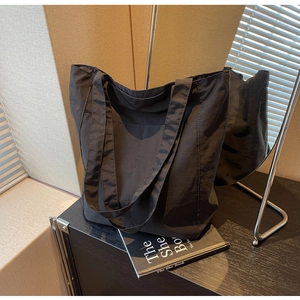 Detail of black nylon tote bag with wide shoulder straps and textured fabric for commuting
