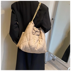 Détail du sac seau matelassé beige en tissu Oxford avec bandoulière chaîne sur modèle