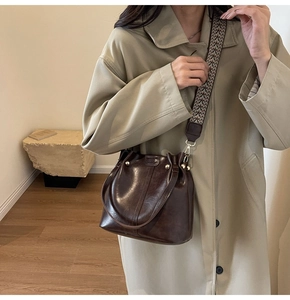 Detail of dark brown retro bucket bag featuring a wide geometric jacquard fabric strap