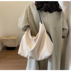 Detail of a large cream nylon crescent bag with stylish black and white rope strap