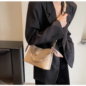 Detail of beige litchi grain leather bag with chain and printed silk scarf wrap