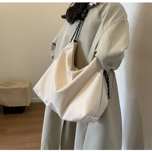 Detail of beige nylon tote bag with black and white braided rope shoulder strap