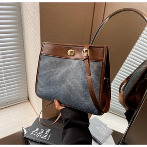 Detail of denim and leather tote with gold twist lock and adjustable shoulder strap