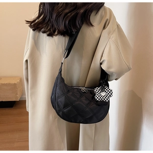Détail du sac demi-lune en nylon matelassé noir avec breloque fleur à damier sur modèle