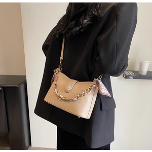 Detail view of khaki pebbled leather crossbody bag with gold chain and floral scarf accessory