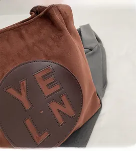 Détail d'un sac cabas marron mat montrant la texture du tissu et le lettrage découpé YELN