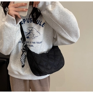 Détail du sac croissant en nylon matelassé avec charme en damier et bandoulière