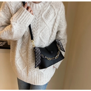 Detail of black crossbody bag with leather strap, gold chain, and printed silk scarf