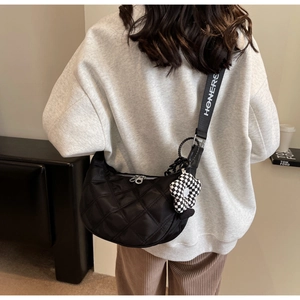 Détail du sac dumpling en nylon matelassé noir avec large bandoulière et breloque