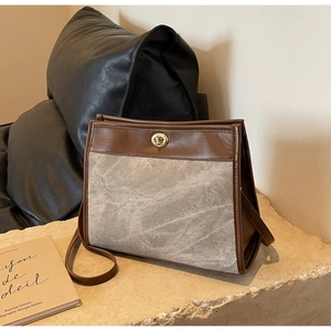 Detail of vintage tote bag featuring brown leather trim and gray textured fabric texture