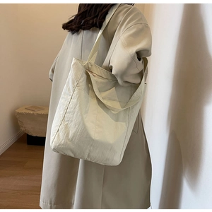 Detail of light beige nylon tote bag with dual straps on khaki trench coat