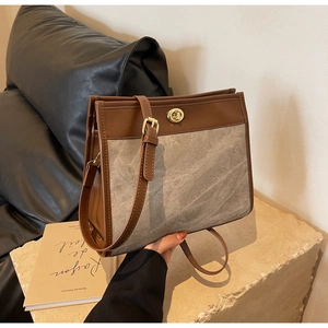 Detail of vintage canvas and brown leather tote bag with a golden metal turn-lock