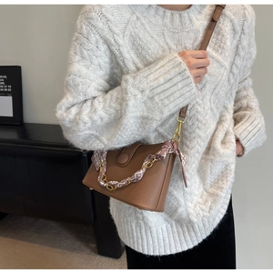 Detail of brown lychee leather bag with floral scarf wrapped chain on a cream sweater