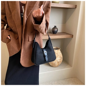 Dettaglio della borsa hobo nera con fibbia in argento indossata da una modella in foto
