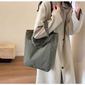 Olive green nylon tote bag shown on a model, highlighting large capacity and daily commute style
