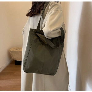 Detail of dark green nylon tote bag showing spacious capacity and smooth texture