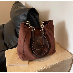 Détail d'un cabas en daim marron avec logo en cuir et bandoulière chaîne dorée