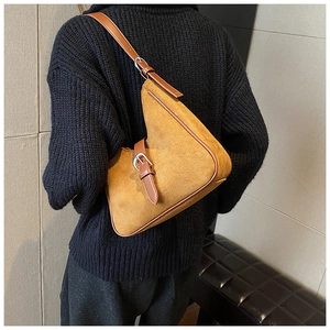 Dettaglio di una borsa sottobraccio vintage in camoscio senape su un maglione nero
