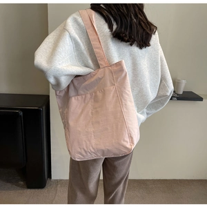 Close-up of pink nylon tote bag showing spacious capacity and front pocket on model