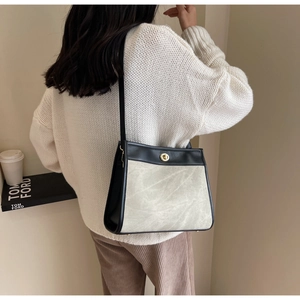 Detail of grey tote bag with black leather flap and golden circular metal lock