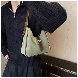 Dettaglio borsa sottobraccio in pelle scamosciata verde con finiture in pelle marrone