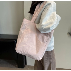 Macro shot of light pink nylon tote bag showing soft fabric texture and front pocket