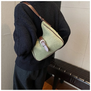 Dettaglio della borsa sottobraccio in tela verde con finiture in pelle marrone e fibbia