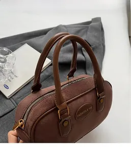 Detail of a brown frosted leather Boston bag with metal logo and zipper closure