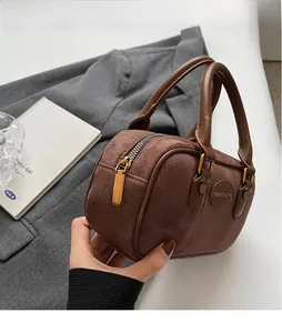 Detail of matte brown suede handbag showing gold zipper and embossed fashion logo