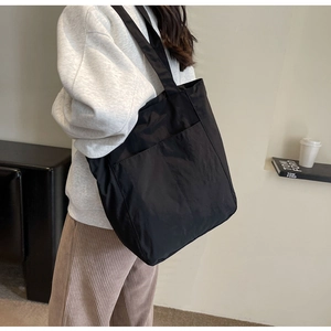 Detailed view of black nylon tote bag featuring two large functional front pockets