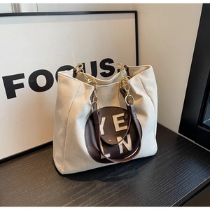 Détail du sac cabas en toile crème avec poignées en cuir marron et chaînes dorées