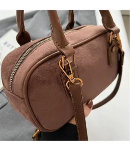 Close-up of golden hardware hooks and texture on a brown frosted retro boston bag