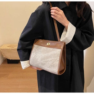 Detail of artistic grey texture and brown leather trim on a minimalist crossbody bag