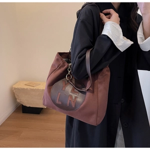 Détail du sac fourre-tout marron mat en suédine avec patch en cuir rond et logo YLN