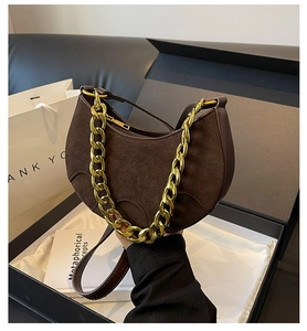 Detail of dark brown suede hobo bag with a chunky gold chain strap in a premium gift box