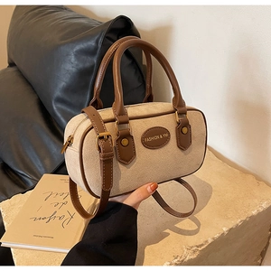 Detail of beige suede Boston bag with brown leather trim and retro gold hardware