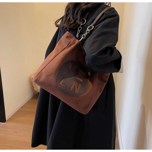 Gros plan du sac cabas en daim marron avec logo YELN et bandoulière en chaîne argentée