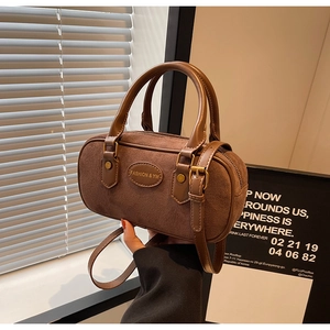 Close-up of retro brown suede cylinder bag with leather trim and fashion logo detail