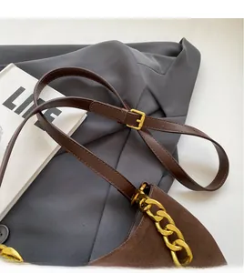 Detail of adjustable leather strap and gold chain on dark brown matte saddle bag