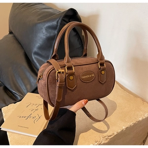 Detail of coffee brown suede mini Boston bag with retro brass hardware and handle