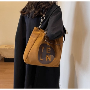 Détail du grand sac cabas mat moutarde avec bandoulière chaîne et écusson logo